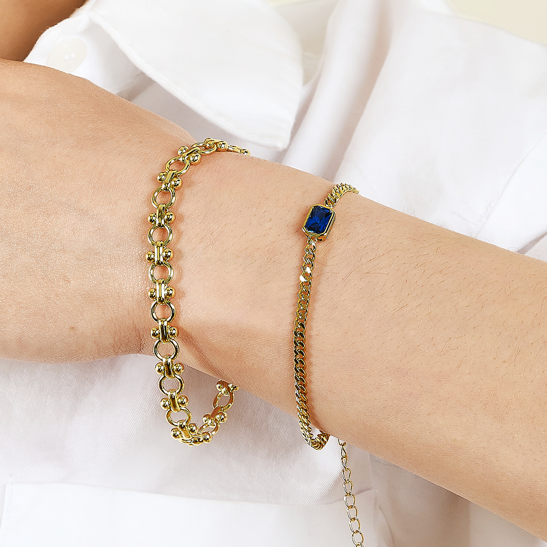 gold chain bracelet inspired by Eiffel tower with gold chain bracelet with blue stone on wrist