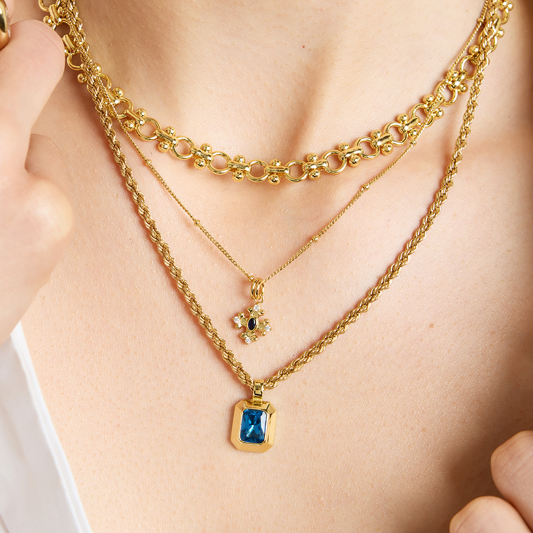 Gold charm with Blue emerald cut cubic zirconia bezel set Inspired by the halls of Versailles on neck 