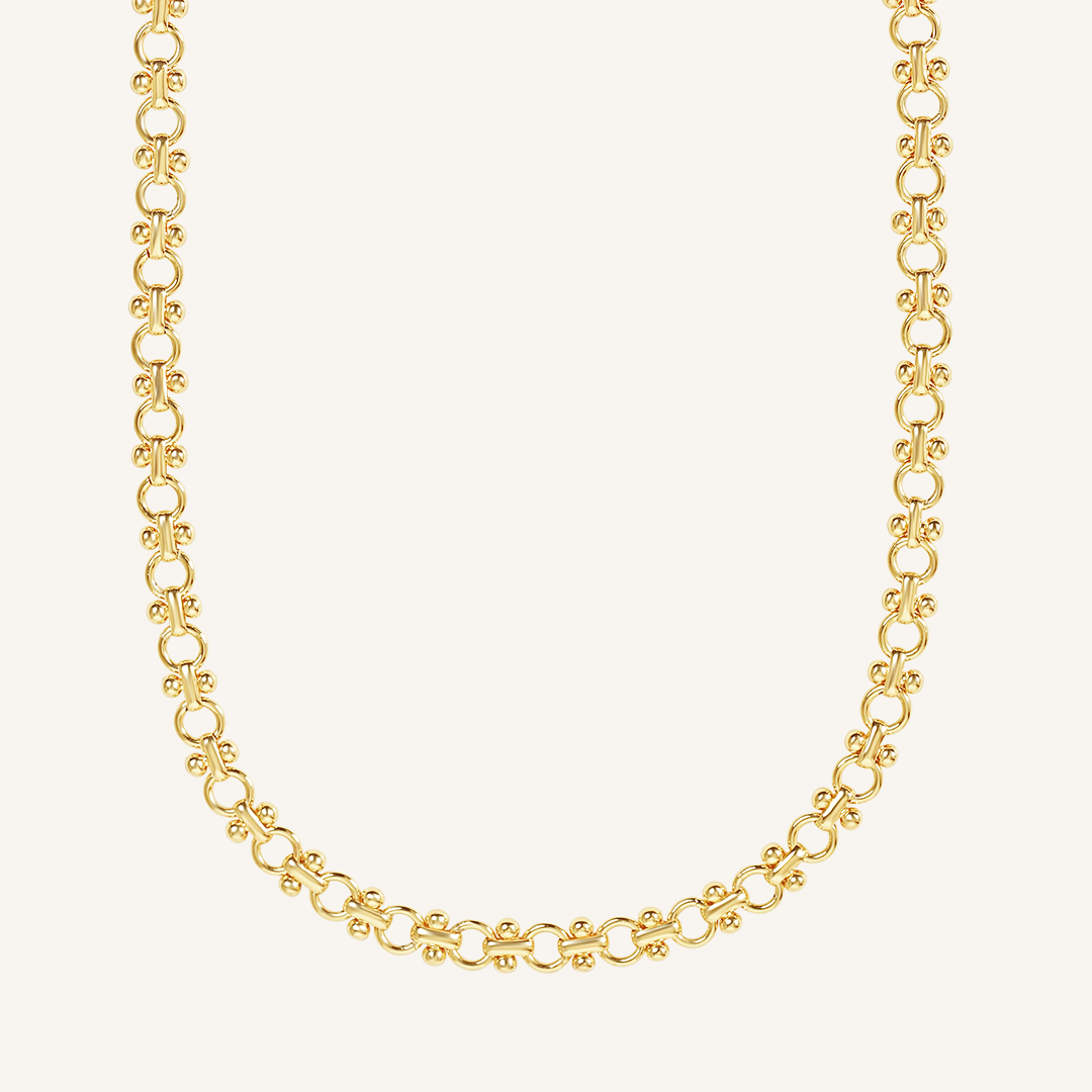 gold chain necklace inspired by Eiffel tower on plain background