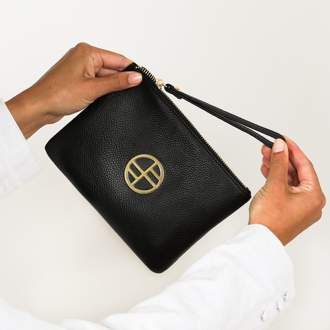 Woman holding black leather pouch bag with gold details on white background