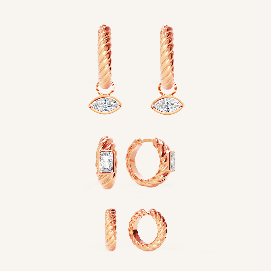 rose gold delicate huggies with a twist design with rose gold hoops inspired by the Louvre's architecture with Marquise cut white cubic zirconias with rose gold hoops inspired by the Louvre's architecture with Marquise cut white cubic zirconias bezel set hoop charms on white background
