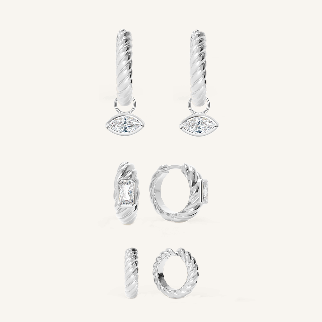 silver delicate huggies with a twist design with silver hoops inspired by the Louvre's architecture with Marquise cut white cubic zirconias with silver hoops inspired by the Louvre's architecture with Marquise cut white cubic zirconias bezel set hoop charms on white background
