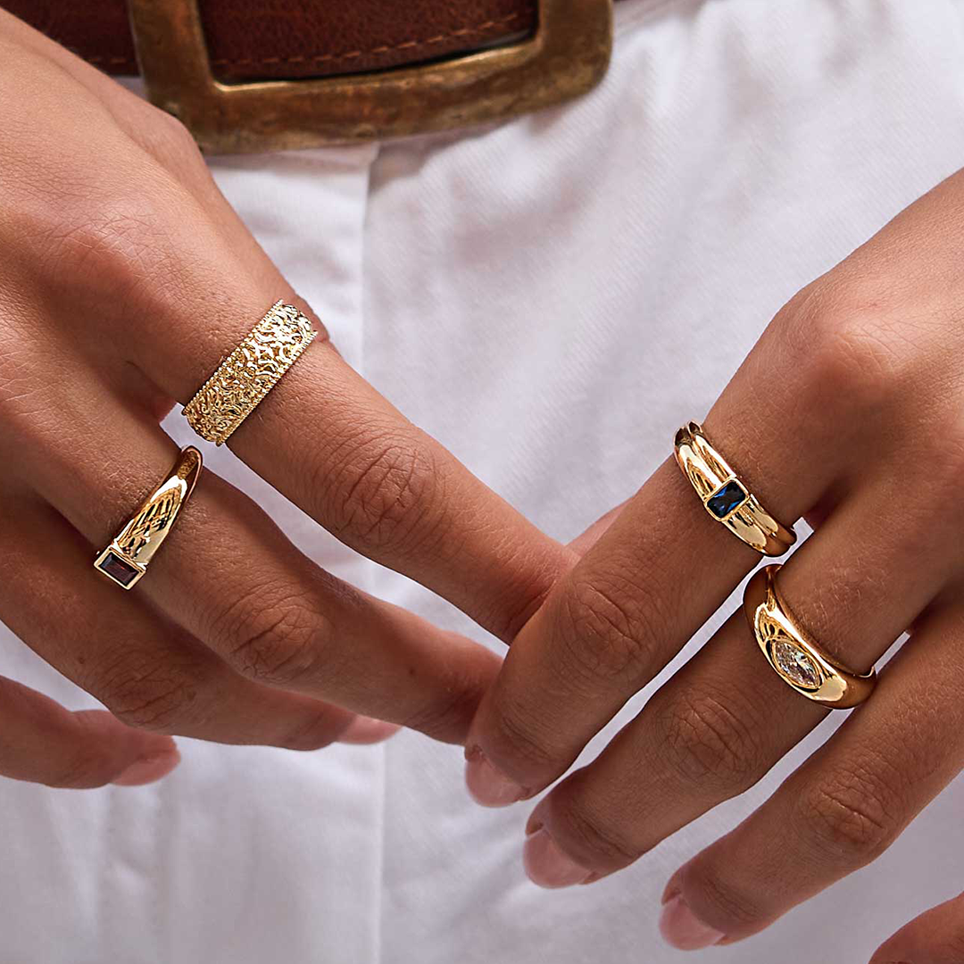 Gold ring with Navy blue cubic zirconia bezel set Inspired by the halls of Versailles on fingers close up on hand with other gold rings