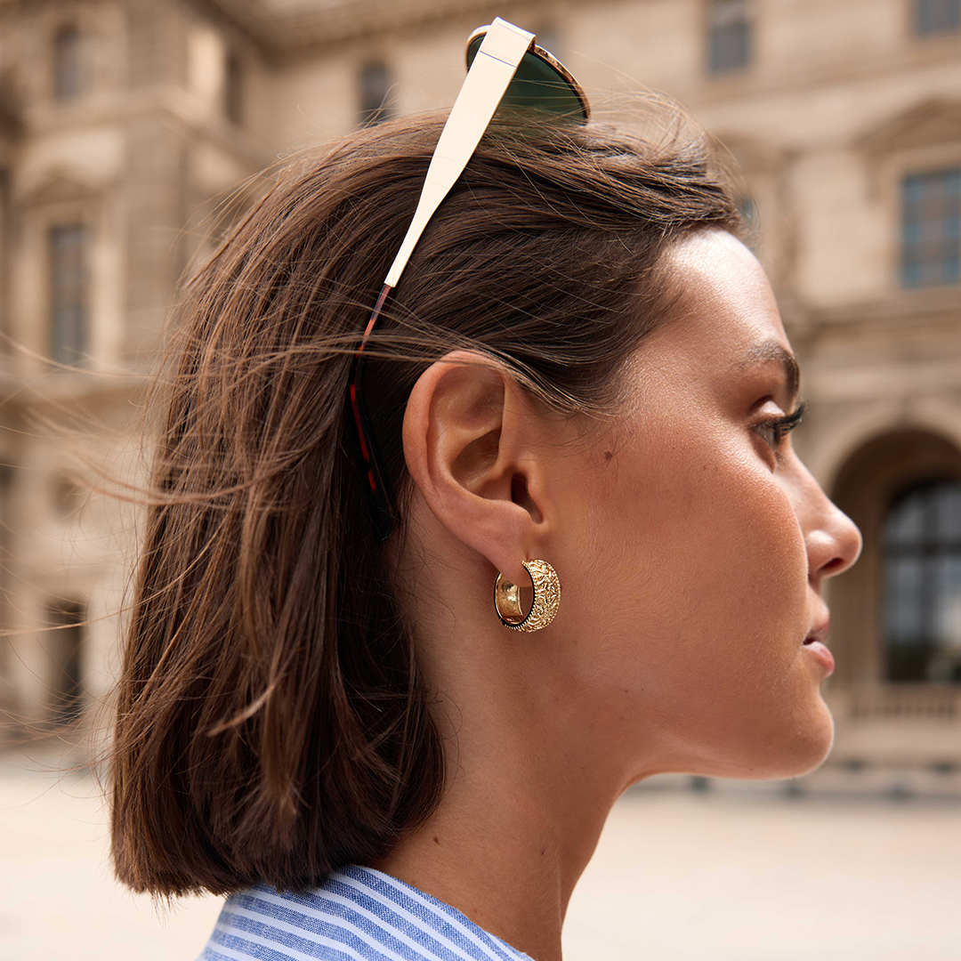 intricately designed statement gold hoops in the ear 