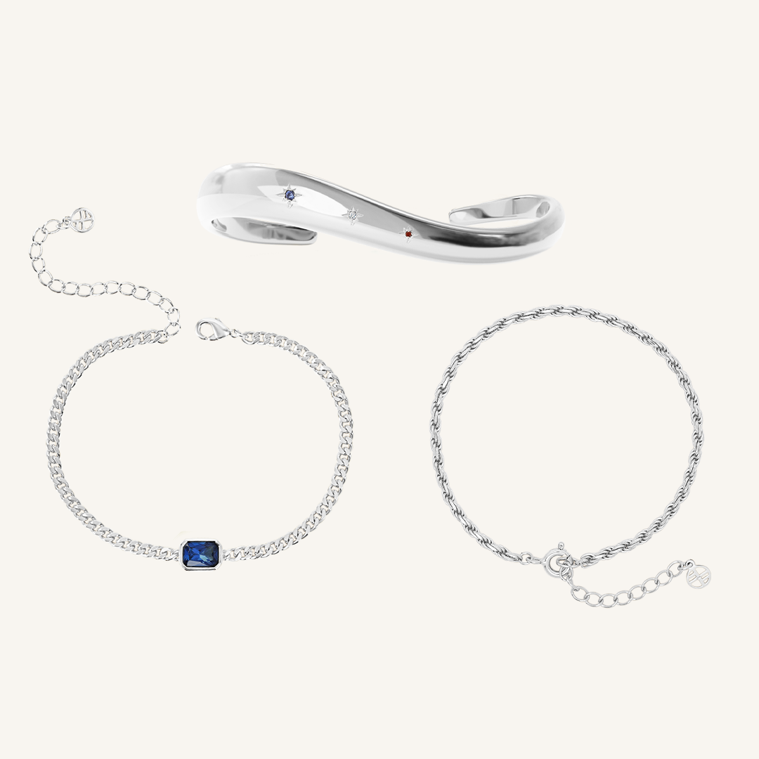 silver chain bracelet with a navy blue cubic zirconia asymmetrical cuff and rope bracelet set on white background 