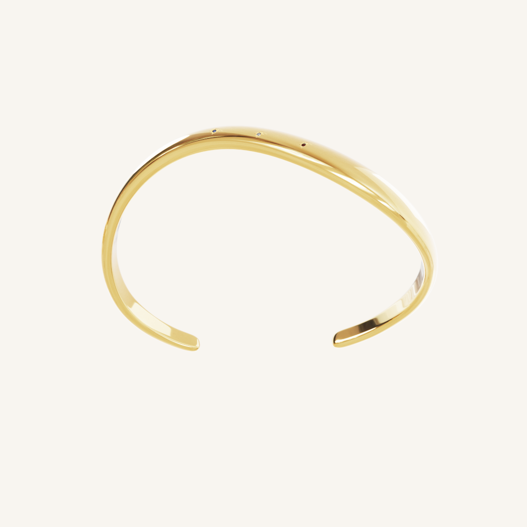 Gold cuff asymmetrical in shape with Navy, white and red cubic zirconias in a row on white background side profile