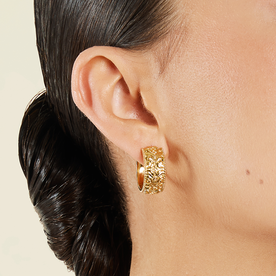 intricately designed statement gold hoops in ear close up