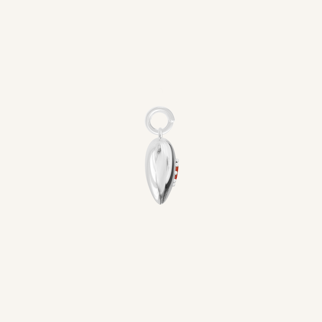 silver heart shaped charm with deep red oval cubic zirconia on white background side profile
