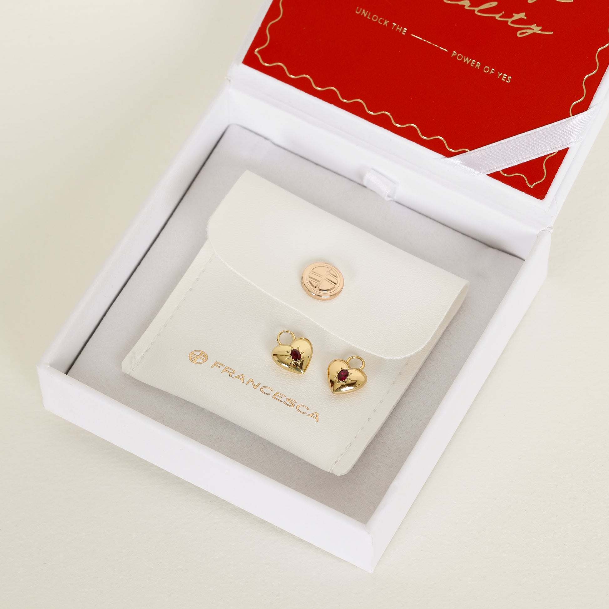 gold hoop charms with heart charms with deep red oval cubic zirconias on white box