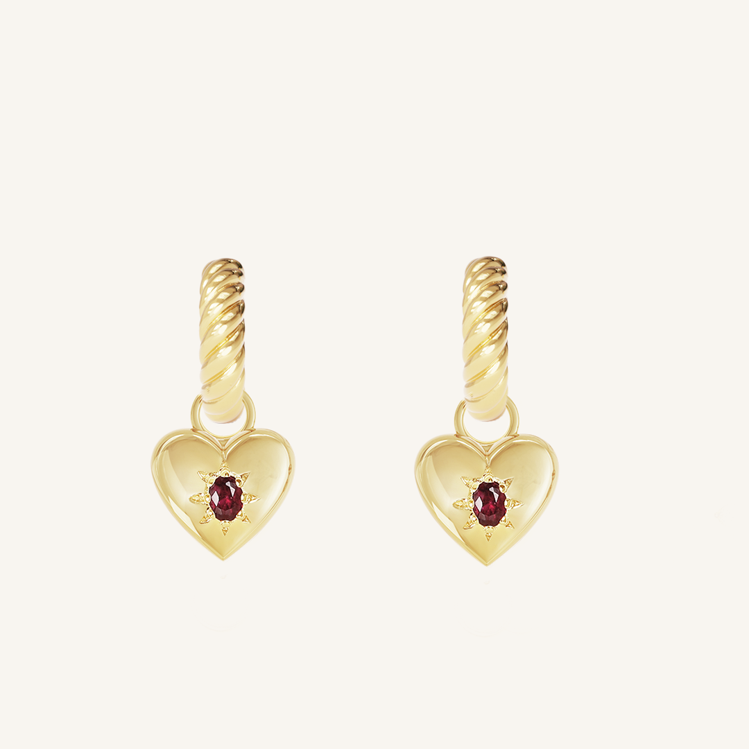 gold hoops with heart charms with deep red oval cubic zirconias on white background