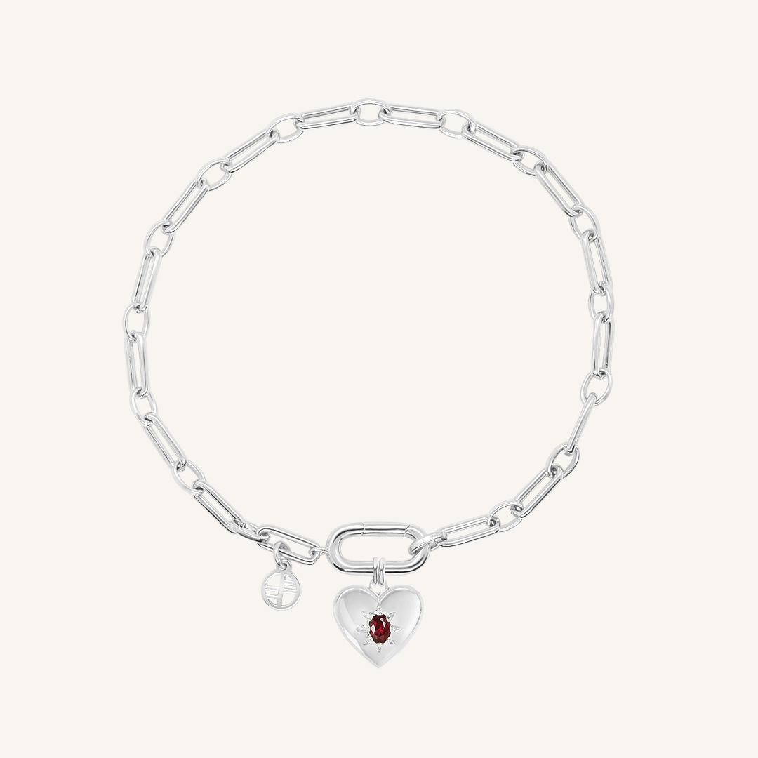 silver heart shaped charm with deep red oval cubic zirconia attached to create link bracelet on white background