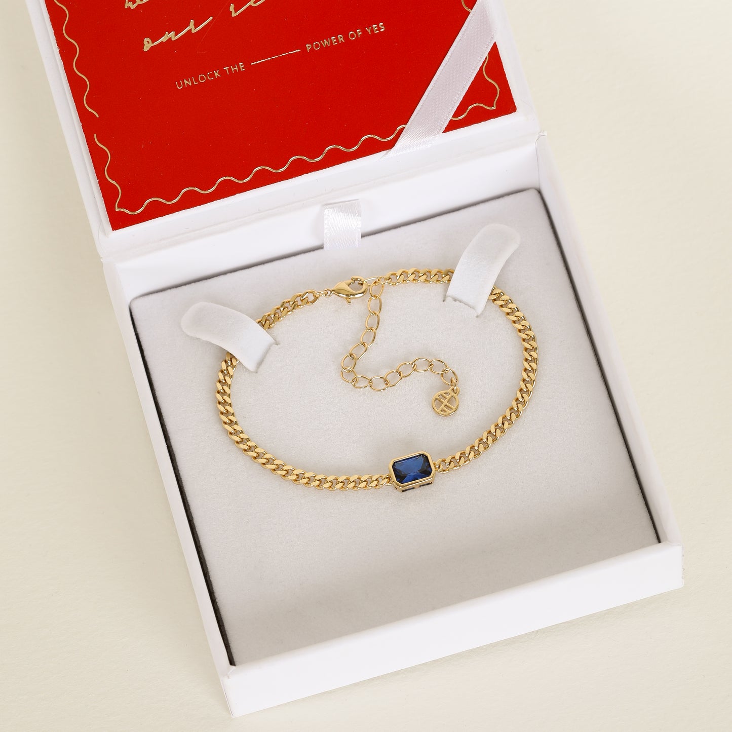 Gold chain bracelet with Navy blue cubic zirconia bezel set in centre Inspired by the halls of Versailles on white bracelet box
