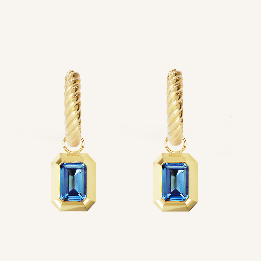 Gold hoops with Blue emerald cut cubic zirconias bezel set Inspired by the halls of Versailles on white background 
