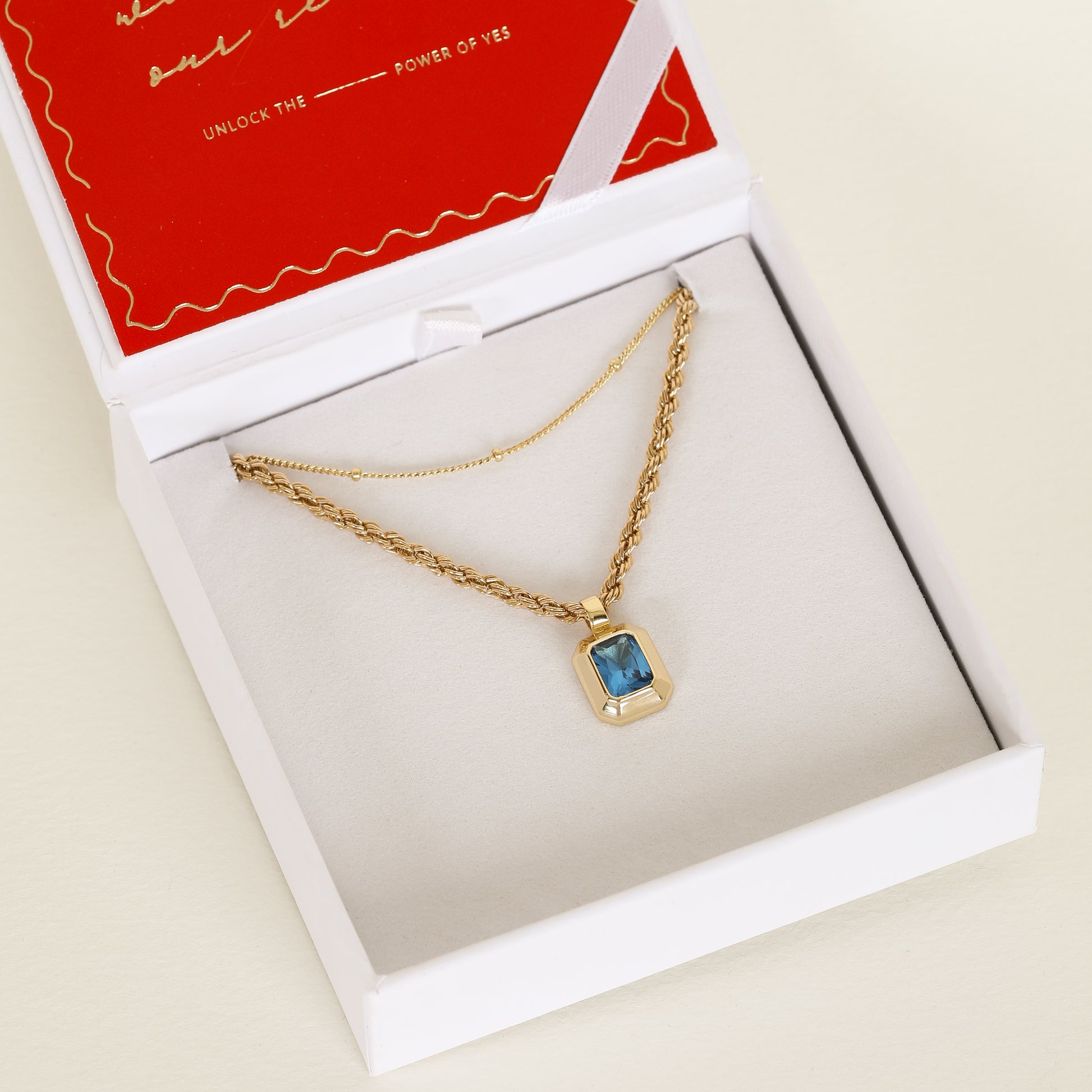 silver charm with Blue emerald cut cubic zirconia bezel set Inspired by the halls of Versailles on rope chain paired with bobble chain in white necklace box 