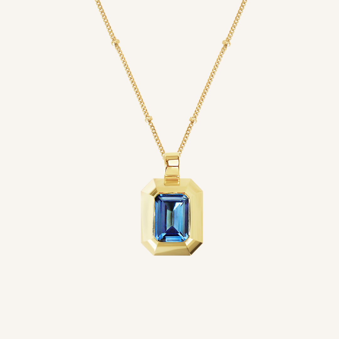 Gold charm with Blue emerald cut cubic zirconia bezel set Inspired by the halls of Versailles on bobble chain on white background 