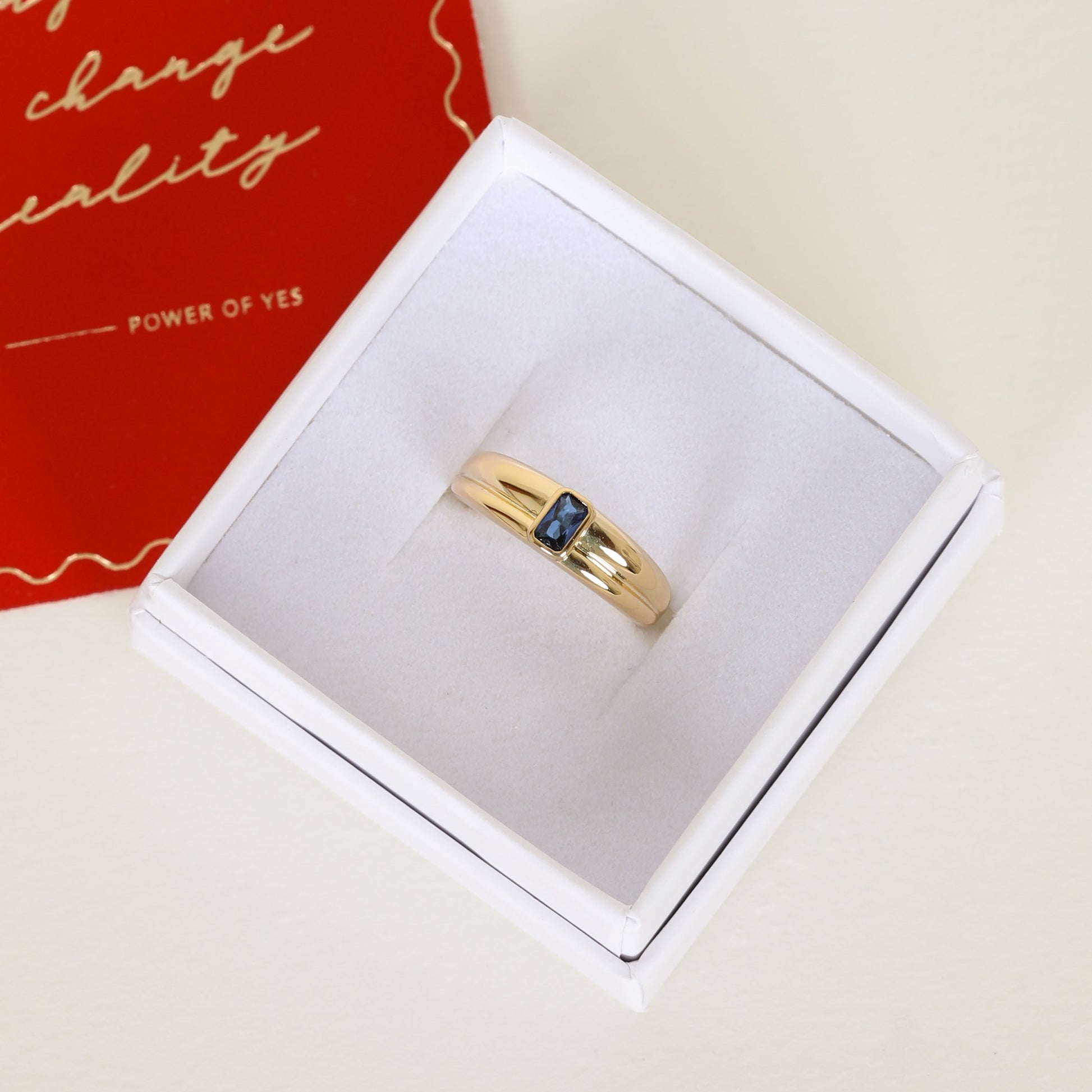 Gold ring with Navy blue cubic zirconia bezel set Inspired by the halls of Versailles on white ring box 