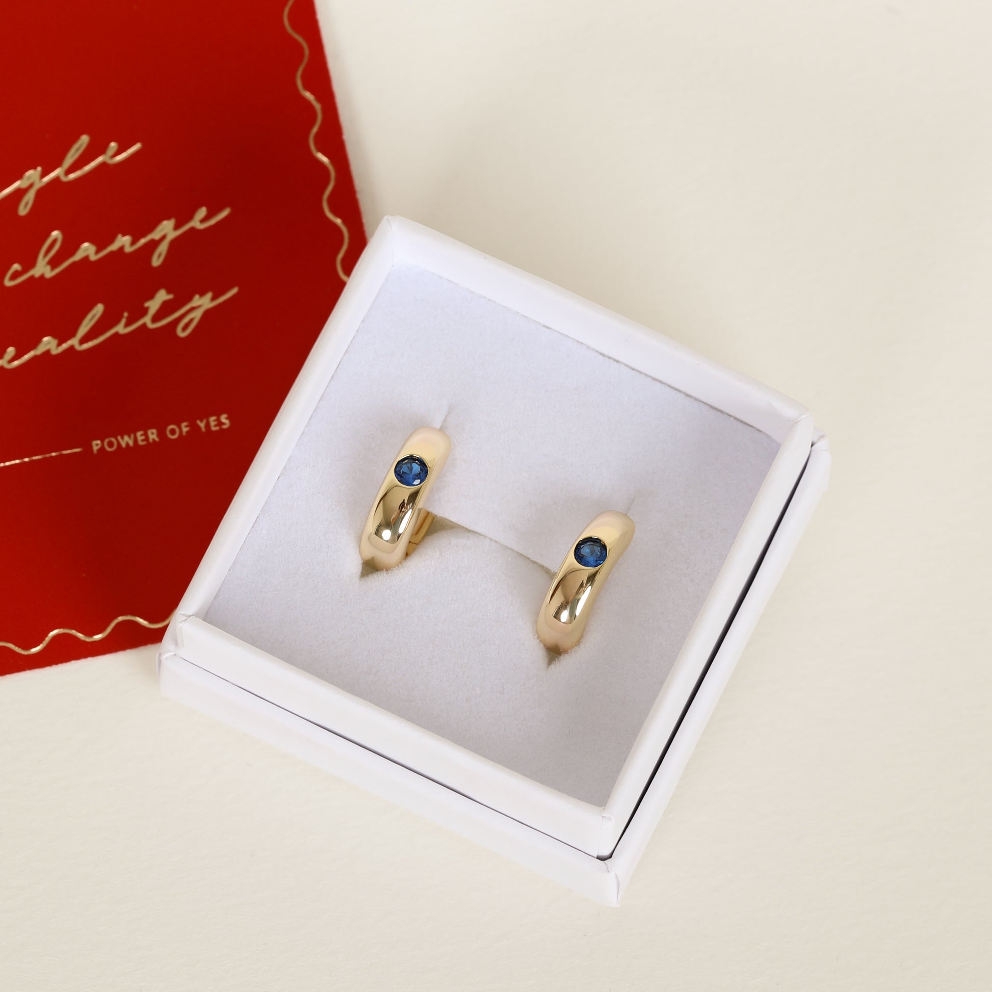 Gold hoops with Navy blue cubic zirconia bezel set Inspired by the halls of Versailles on white earring box