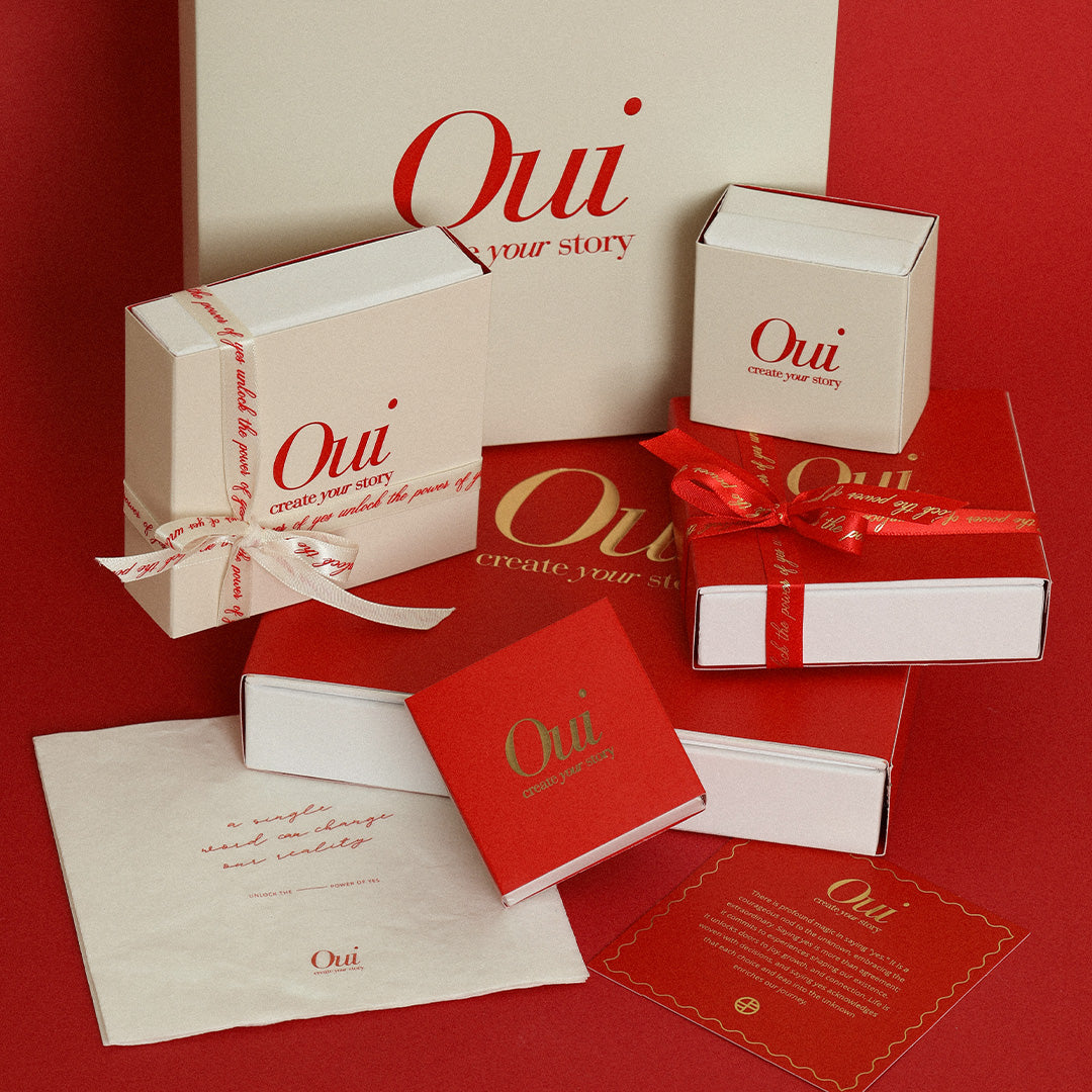 Red, gold and white gift wrapping and ribbon on red background inspired by Paris and the word Oui
