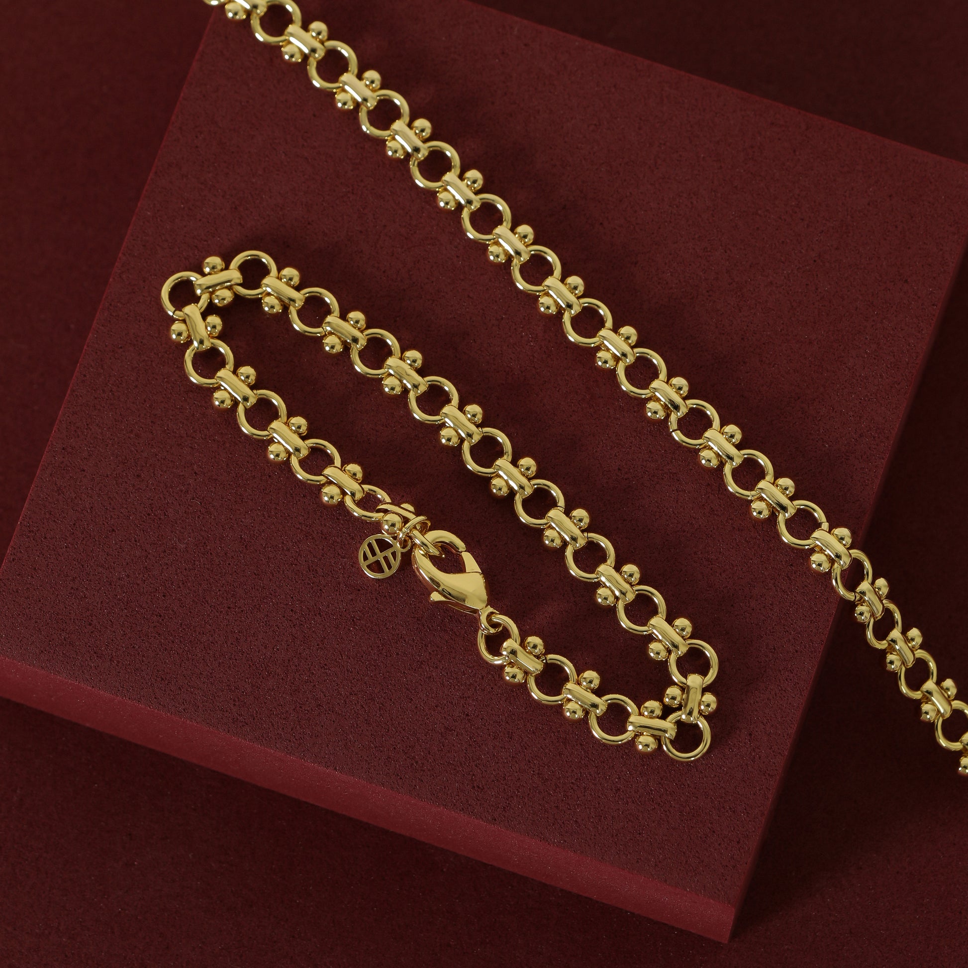 gold chain bracelet and chain necklace set inspired by Eiffel tower on plain red background