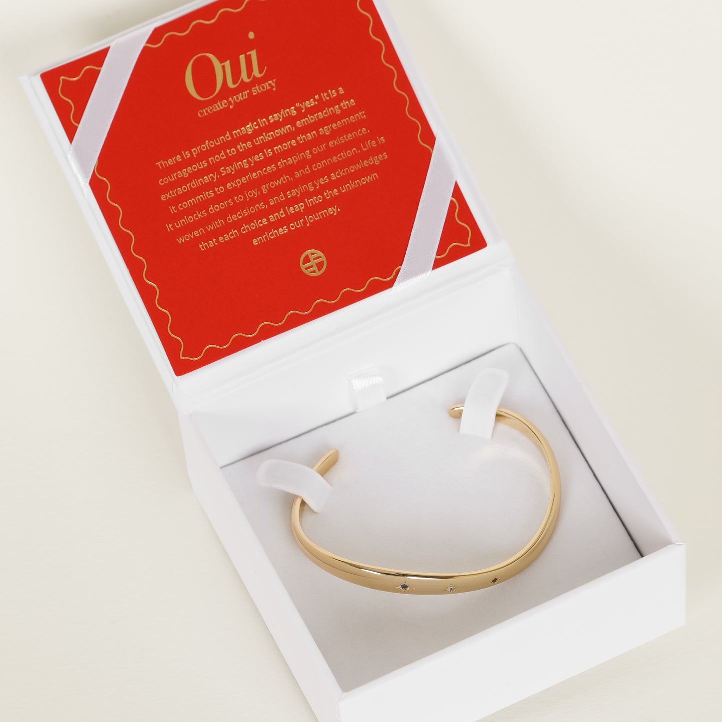 Gold cuff asymmetrical in shape with Navy, white and red cubic zirconias in a row on white bracelet box 