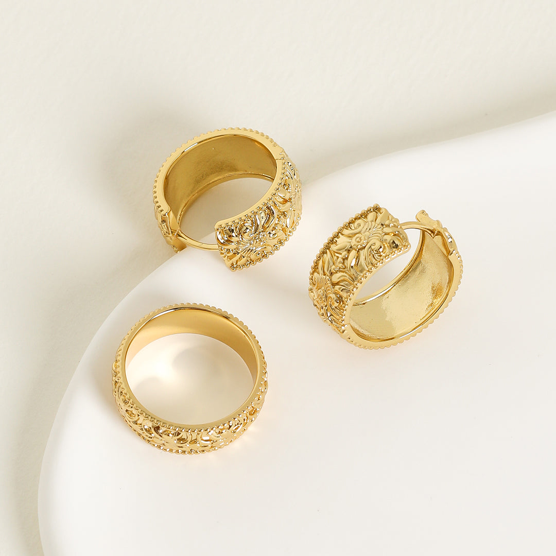 intricately designed statement gold ring with intricately designed statement gold hoops inspired by Paris on white background